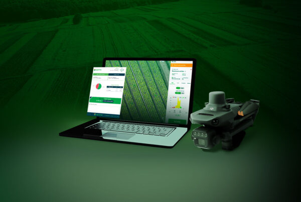 Laptop showing agricultural analytics dashboards beside a drone on a green-tinted field background.