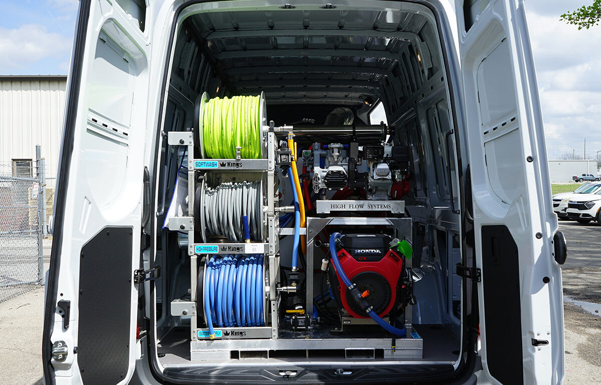 Rear of a white work van with mounted hose reels and a Honda engine for high-flow pressure washing, neon green and blue hoses visible in racks